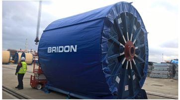 Image of a BBRG employee standing next to a Bridon wire rope reel. The image displays proper storage of large wire rope reels where it is not practical to have them sheltered. 